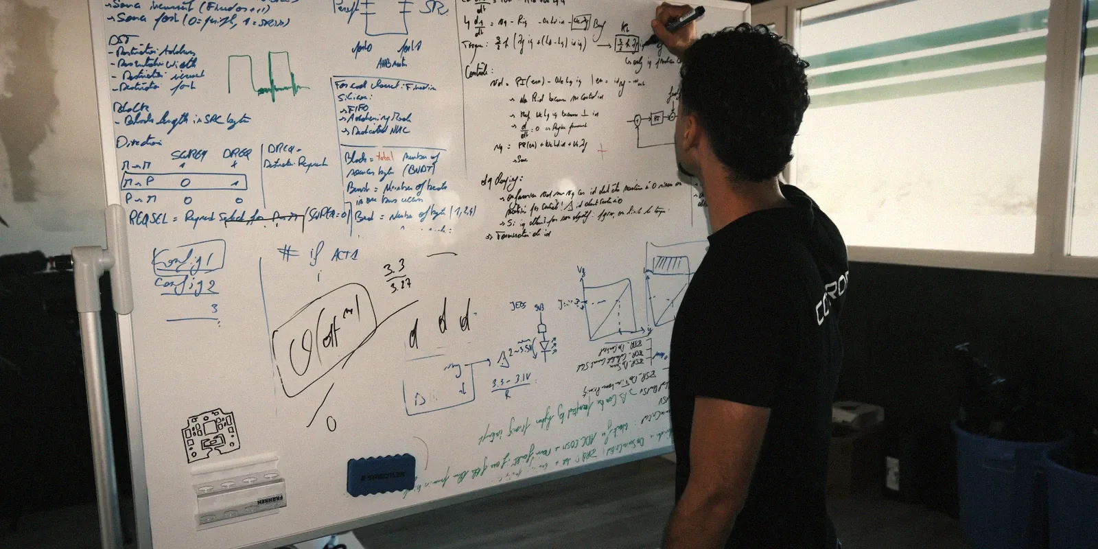 A coprod engineer working through field-oriented control equations and EtherCAT register maps on a whiteboard